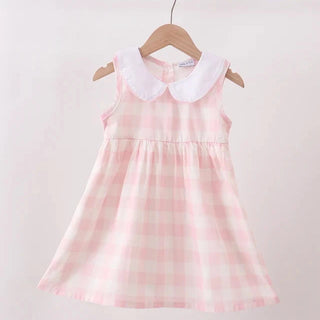 A sleeveless baby girl's dress with a pink and white gingham pattern and a white Peter Pan collar, hanging on a wooden hanger from a light wood rod against a plain off-white background.