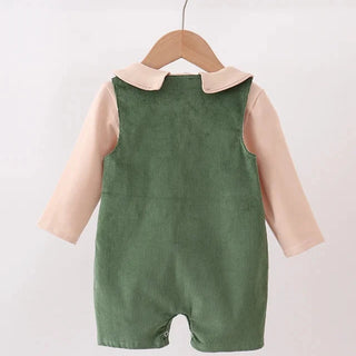 Green baby romper with pink long-sleeve shirt on a hanger against a white background