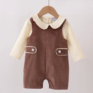 A baby romper hanging on a wooden hanger, featuring a brown corduroy-style overall vest over a cream long-sleeve shirt with a Peter Pan collar.