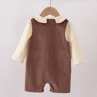 A baby romper hanging on a wooden hanger, featuring a brown corduroy-style sleeveless vest over a cream long-sleeve shirt with a Peter Pan collar.