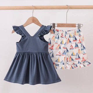 Children's blue top and sailboat-patterned shorts on hangers against a white background