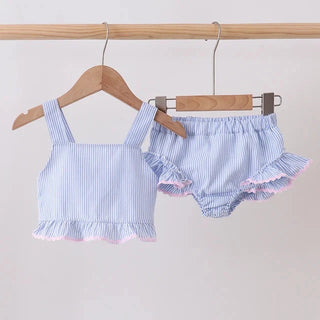 A two-piece baby swim set consisting of a light blue and white striped tank top and matching ruffled bloomers, hanging from wooden hangers on a wooden clothing rack against a plain light background.