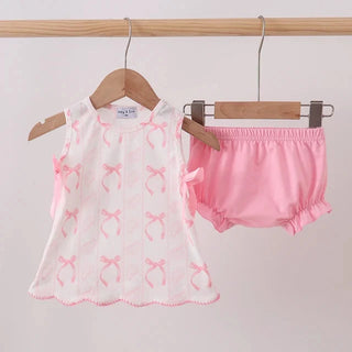 Baby outfit with pink bow-patterned top and bloomers hanging on a rack.