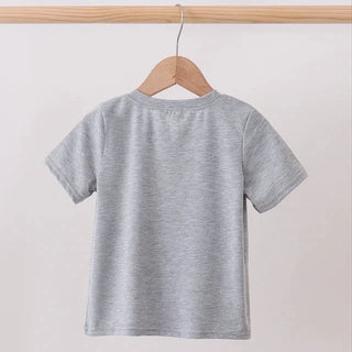 A light gray short-sleeve t-shirt hanging on a wooden hanger from a wooden clothing rack against a plain off-white wall.
