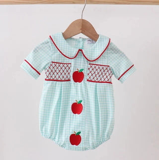 Baby romper with red apple design on a hanger against a white background
