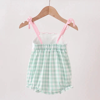 A baby romper with a mint green and white gingham pattern, featuring pink shoulder straps tied in bows, hanging on a wooden hanger against a plain light background.