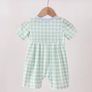 Green and white checkered baby romper on a wooden hanger against a light gray background