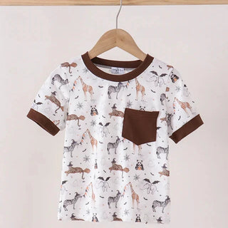 A short-sleeve kids' t-shirt with an all-over dog print, featuring solid brown trim on the collar, sleeve cuffs, and a matching brown chest pocket, hanging on a wooden hanger.