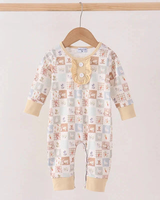 A baby long-sleeve footless romper hanging on a wooden hanger against a plain light background. The romper features a patchwork animal print in soft beige, brown, and muted blue tones, with a beige ruffled collar and snap-button neckline.