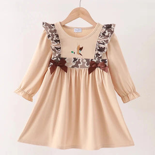 A beige long-sleeve dress with camouflage-patterned shoulder straps and brown bows, hanging on a wooden hanger against a plain white background.