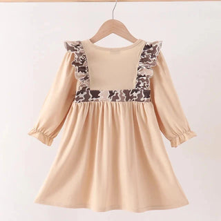 A beige long-sleeve dress with brown and beige patterned ruffle trim on the shoulders, hanging on a wooden hanger against a plain light background.