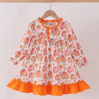A toddler girl's long-sleeve dress with a white base, orange pumpkin print, and bright orange ruffle trim at the hem, hanging on a wooden hanger against a plain light background.