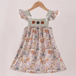 A toddler girl's sleeveless dress with a ruffled neckline and flutter sleeves, featuring an all-over autumn pumpkin and leaf print. It is displayed on a wooden hanger against a neutral, light beige background.