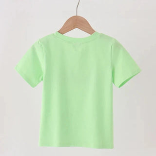 A light green short-sleeve t-shirt hanging on a wooden hanger from a wooden clothes rack against a plain white wall.