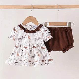 A baby girl's two-piece outfit hanging on wooden hangers from a clothing rack. The set includes a white short-sleeve ruffled blouse with a brown collar and an all-over animal print, paired with solid dark brown bloomers.