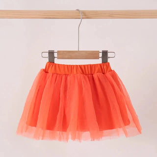 A bright orange tulle tutu skirt hanging from a wooden hanger on a clothing rack against a plain light background.