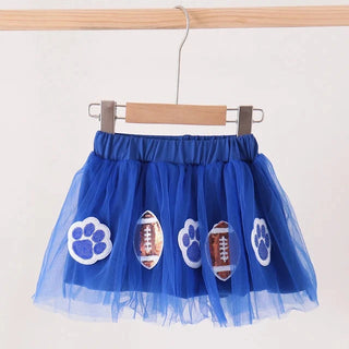 A royal blue tulle tutu skirt with paw print and football appliques, hanging from a wooden hanger on a wooden clothes rack against a plain white wall.
