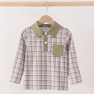 A children's long-sleeve plaid shirt hanging on a wooden hanger against a plain light background. The shirt has a beige, brown, and white plaid pattern with an olive green collar and matching green chest pocket.