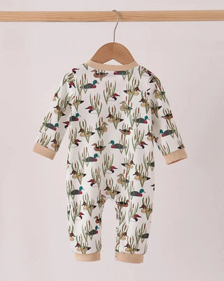 A baby long-sleeve footless one-piece jumpsuit with an all-over duck and reeds print, hanging on a wooden hanger from a light wood rod against a plain light background.