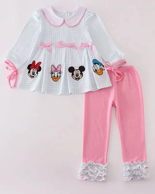 Children's outfit with a white top featuring cartoon characters and pink pants on a light pink background