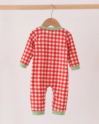 A baby long-sleeve footless jumpsuit with a red and white gingham check pattern and sage green trim, hanging on a wooden hanger from a light wood rod against a plain light background.