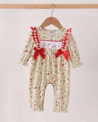 A baby girl's long-sleeve romper hanging on a wooden hanger against a plain light background. The romper has a cream-colored base with a small red and multicolor print, red-and-white gingham shoulder straps, and red ribbon bows at the waist.
