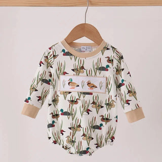 A baby long-sleeve romper with a duck and reeds print, hanging on a wooden hanger against a plain light background.