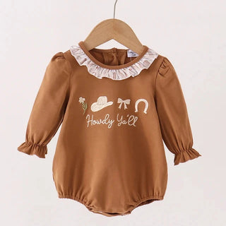 A baby long-sleeve romper in a warm brownish-copper color, hanging on a wooden hanger. The romper features a white ruffled collar, ruffled cuffs, and a western-themed graphic on the chest with a hat, bow, horseshoe, and the text 'Howdy Yell'.