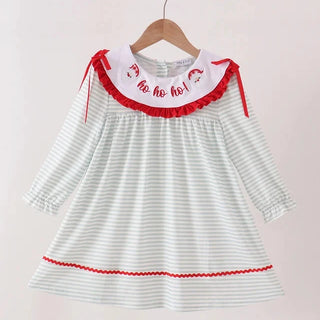 A toddler girl's long-sleeve dress with white and light green stripes, featuring a white Peter Pan collar with red ruffles and 'ho ho ho!' embroidery, hanging on a wooden hanger against a light beige background.