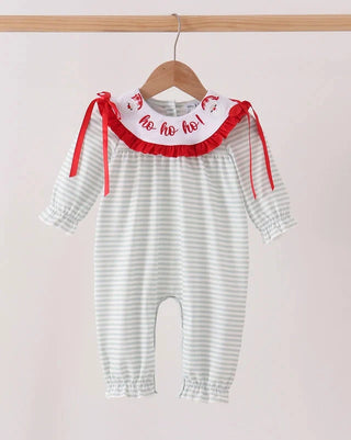 A baby romper with white and light gray stripes, featuring a white ruffled collar with red 'ho ho ho!' lettering and red ribbon ties, hanging on a wooden hanger.