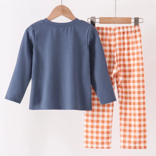 A children's two-piece clothing set hanging on a wooden hanger bar. The set includes a slate blue long-sleeve top and orange-and-white gingham check pants.