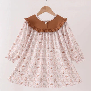 A toddler girl's long-sleeve dress hanging on a wooden hanger against a plain light background. The dress features a light pink and white patterned body with a contrasting brown ruffled Peter Pan collar.