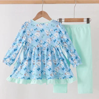 A children's two-piece outfit hanging on wooden hangers against a plain light background. The set includes a long-sleeve dress in light blue with a white and blue goose print and a ruffled mint green hem, paired with matching mint green leggings.