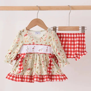 A baby girl's two-piece outfit set hanging on wooden hangers against a plain light background. The set includes a long-sleeve dress with a cream base, red and white gingham trim, and a white waistband with red gingham accents, paired with matching red and white gingham bloomers.