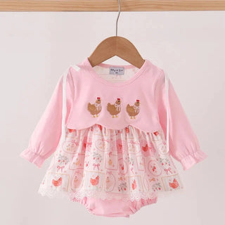 A pink long-sleeve baby romper with a ruffled skirt, hanging on a wooden hanger. The top is solid pink with three embroidered chickens, while the ruffled skirt is white with a pink chicken and egg pattern and lace trim.