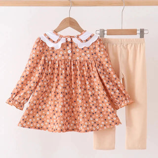 A toddler girl's two-piece outfit set hanging on wooden hangers against a plain white wall. The set includes a long-sleeve peach-orange floral print top with a white Peter Pan collar, and solid beige leggings.