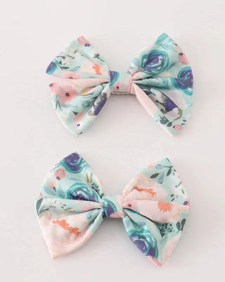Two hair bows with a green garden serenity print on a white background.