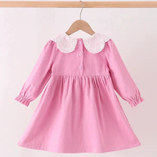 A pink long-sleeve girls dress with a white eyelet Peter Pan collar and button details, hanging on a wooden hanger against a plain light background.