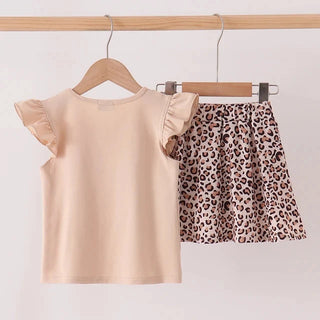 A two-piece girls' outfit set hanging on wooden hangers from a light wood rail. The set includes a light peach-beige short-sleeve top with ruffled sleeves and a matching leopard-print mini skirt in beige, brown, and black.