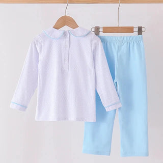 A two-piece children's outfit hanging on wooden hangers against a plain light background. The set includes a white long-sleeve top with a small blue polka dot pattern and light blue collar/cuff trim, paired with light blue pants.