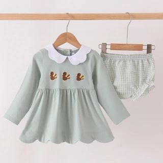 A baby girl's two-piece outfit set hanging on wooden hangers against a plain light background. The set includes a sage green long-sleeve dress with a white Peter Pan collar and three small embroidered brown birds on the chest, paired with matching sage green and white gingham check bloomers.