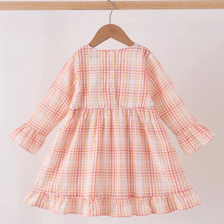 A long-sleeve girls dress with a white and orange plaid pattern, hanging on a wooden hanger from a light wood clothing rack against a plain white wall.