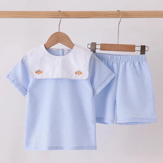 A light blue children's two-piece outfit set consisting of a short-sleeve top and matching shorts, hanging on wooden hangers against a plain white background.