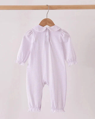 A baby's long-sleeve footless romper in a very light pink and white micro-dot pattern, hanging on a wooden hanger from a light wood rod against a plain off-white background.