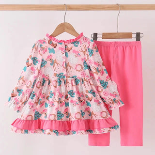 A two-piece children's outfit hanging on wooden hangers against a plain light background. The set includes a long-sleeve tiered blouse with a pink, teal, and orange animal print on a white base, and solid bright pink leggings.
