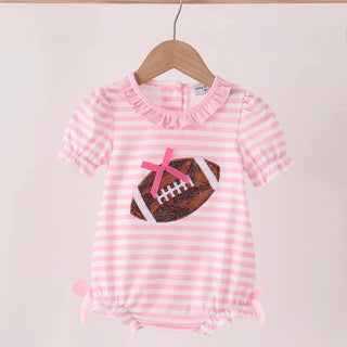 A pink and white striped baby romper with ruffled trim and a football applique on the chest, hanging on a wooden hanger against a light pink background.