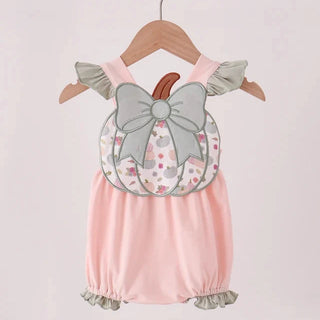 A baby romper in light pink with a decorative applique of a gray bow and a pumpkin pattern on the chest, hanging on a wooden hanger against a light pink background.