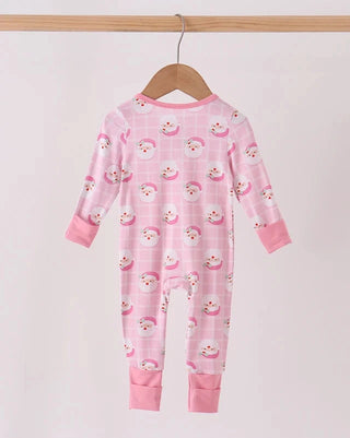 A pink baby jumpsuit with a plaid pattern and a repeating snowman print, hanging on a wooden hanger from a wooden clothes rack against a plain light background.