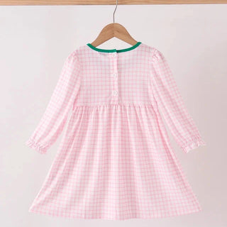 A pink and white gingham long-sleeve baby dress hanging on a wooden hanger against a plain light background.
