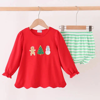 A children's two-piece outfit hanging on wooden hangers against a plain light background. The set includes a bright red long-sleeve top with small Christmas-themed appliques (a gingerbread man, a tree, and a snowman) on the chest, and green-and-white striped bloomers.